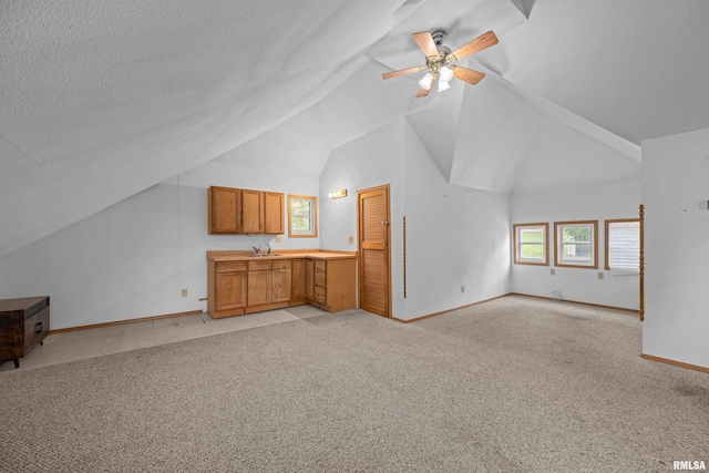 unfurnished living room featuring vaulted ceiling, light carpet, baseboards, ceiling fan, and a sink