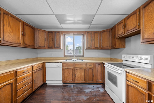 kitchen featuring white appliances, a sink, brown cabinetry, light countertops, and a drop ceiling