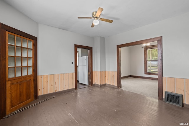spare room with a wainscoted wall, wooden walls, a ceiling fan, hardwood / wood-style flooring, and baseboards