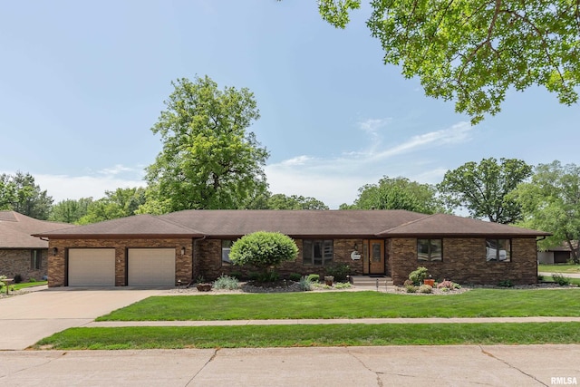 view of front facade with an attached garage, a front lawn, driveway, and brick siding