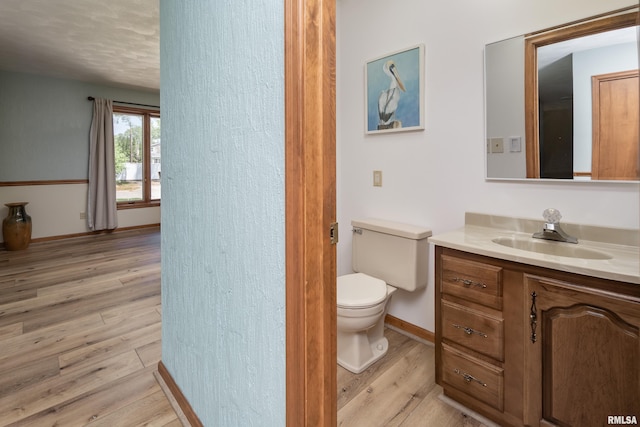 bathroom with wood finished floors, vanity, toilet, and baseboards