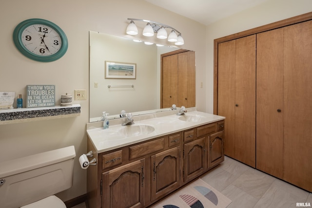 full bathroom with toilet, double vanity, and marble look tile flooring