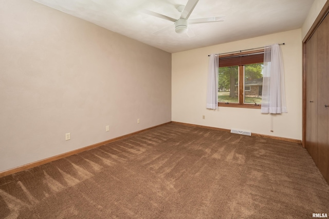 unfurnished room featuring dark carpet, a ceiling fan, and baseboards