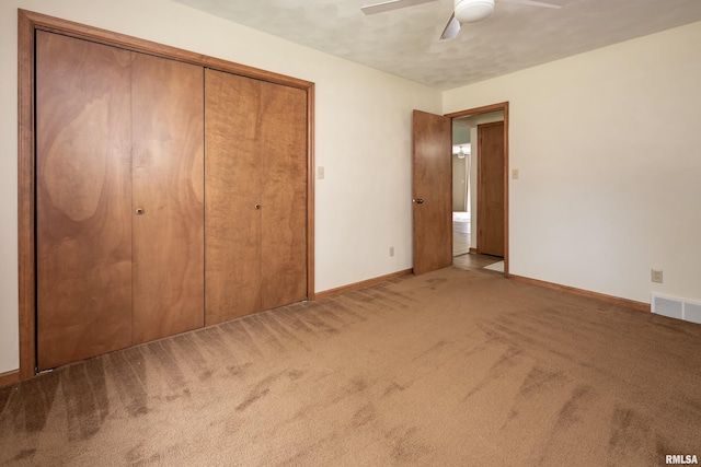 unfurnished bedroom featuring carpet, baseboards, a closet, and a ceiling fan