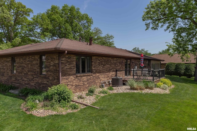 view of side of home featuring brick siding, a wooden deck, central AC, and a yard