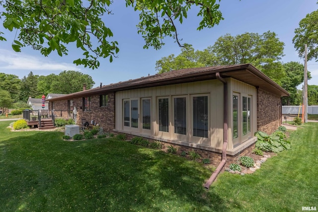 rear view of house with a wooden deck, a yard, and brick siding