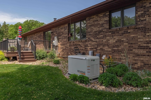 view of side of home with a deck, a lawn, and brick siding