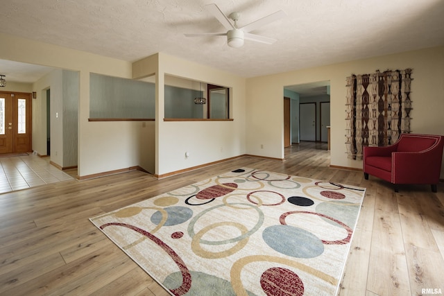 living room featuring hardwood / wood-style flooring, a ceiling fan, baseboards, and a textured ceiling