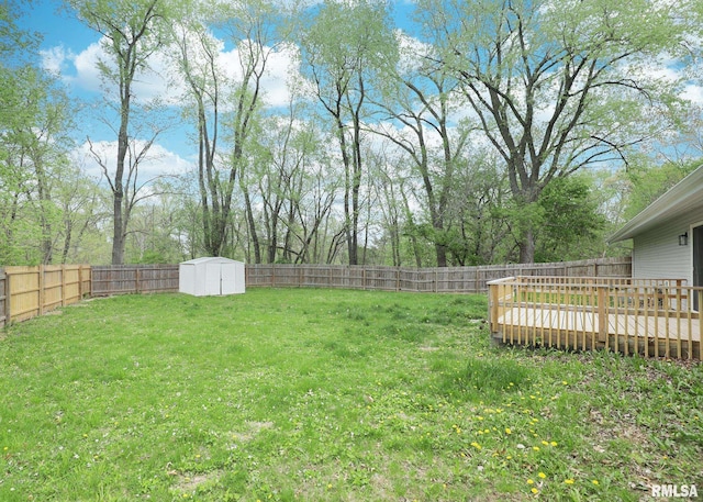 view of yard with a wooden deck, a storage unit, and an outbuilding