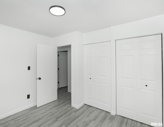 unfurnished bedroom with baseboards, light wood-type flooring, and a closet