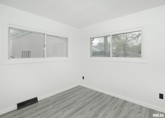 spare room featuring baseboards, wood finished floors, and healthy amount of natural light