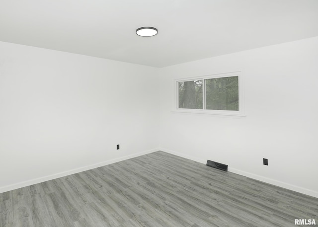 spare room featuring baseboards and wood finished floors