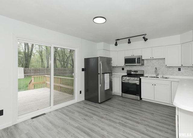 kitchen featuring appliances with stainless steel finishes, a sink, light countertops, and tasteful backsplash