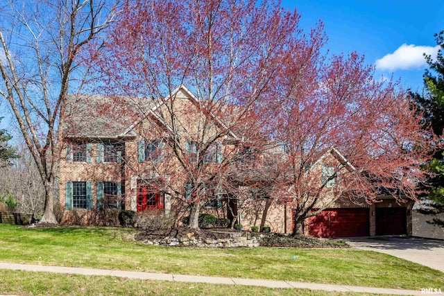 6800 Ridges Ct, Bettendorf, IA 52722 - view of property hidden behind natural elements with a garage, brick siding, a front yard, and concrete driveway