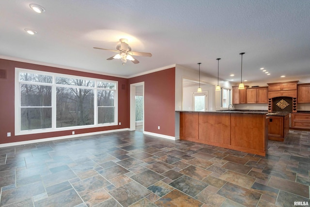 6800 Ridges Ct, Bettendorf, IA 52722 - kitchen featuring baseboards, stone tile floors, brown cabinetry, ceiling fan, and healthy amount of natural light