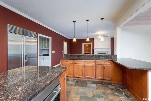 6800 Ridges Ct, Bettendorf, IA 52722 - kitchen featuring stainless steel appliances, ceiling fan, stone finish flooring, a fireplace, and brown cabinets