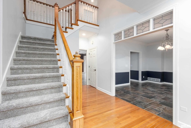 6800 Ridges Ct, Bettendorf, IA 52722 - staircase featuring ornamental molding, baseboards, a high ceiling, a chandelier, and stone finish floors