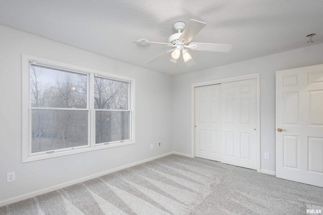 6800 Ridges Ct, Bettendorf, IA 52722 - unfurnished bedroom featuring carpet flooring, baseboards, a closet, a textured ceiling, and a ceiling fan
