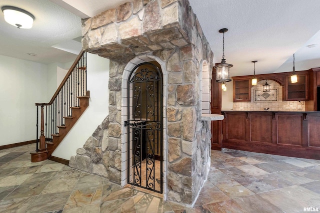 6800 Ridges Ct, Bettendorf, IA 52722 - stairs featuring stone tile floors, baseboards, arched walkways, and a textured ceiling