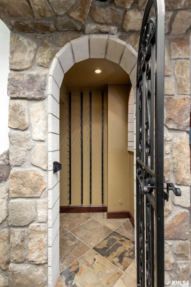 6800 Ridges Ct, Bettendorf, IA 52722 - wine area with arched walkways, stone finish flooring, and baseboards