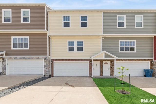 725 Cox Ct, Le Claire, IA 52753 - multi unit property featuring a garage, concrete driveway, a front lawn, and stone siding