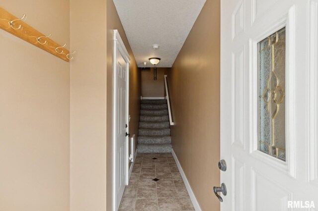 725 Cox Ct, Le Claire, IA 52753 - hallway with baseboards, light tile patterned floors, stairway, and a textured ceiling