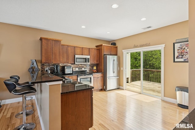 725 Cox Ct, Le Claire, IA 52753 - kitchen featuring appliances with stainless steel finishes, baseboards, a peninsula, tasteful backsplash, and a kitchen bar