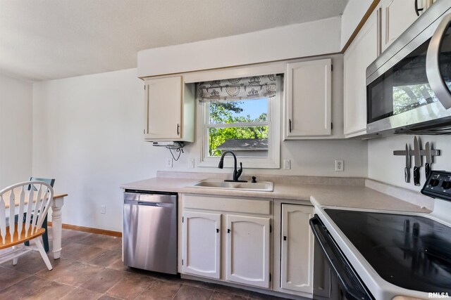 5812 N Thornwood Ave, Davenport, IA 52806 - kitchen featuring stainless steel appliances, a sink, light countertops, baseboards, and white cabinets