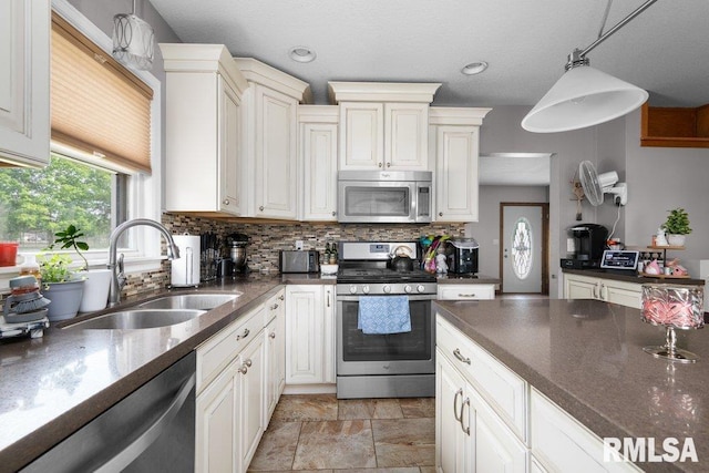 3430 W Locust St, Davenport, IA 52804 - kitchen featuring appliances with stainless steel finishes, tasteful backsplash, a sink, decorative light fixtures, and light stone finish floors