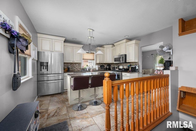 3430 W Locust St, Davenport, IA 52804 - kitchen with stainless steel appliances, decorative backsplash, a kitchen island, a sink, and stone finish floors