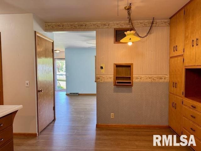 1003 16th Ave N, Clinton, IA 52732 - kitchen with wood finished floors, light countertops, baseboards, decorative light fixtures, and brown cabinets