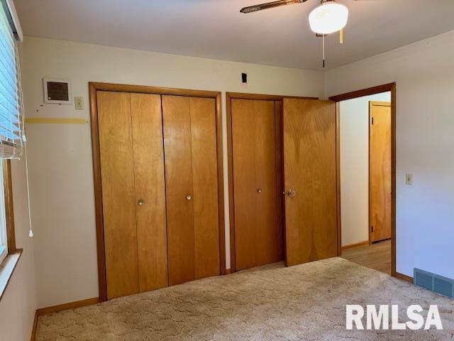 1003 16th Ave N, Clinton, IA 52732 - carpeted bedroom with multiple closets, baseboards, and a ceiling fan