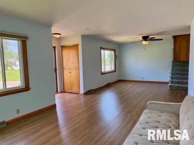 1003 16th Ave N, Clinton, IA 52732 - unfurnished living room featuring wood finished floors, stairs, baseboards, and ceiling fan