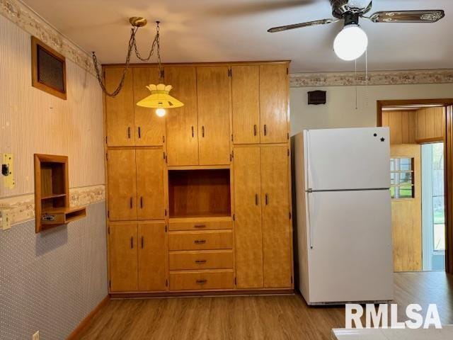 1003 16th Ave N, Clinton, IA 52732 - kitchen with freestanding refrigerator, light wood-style flooring, a ceiling fan, and brown cabinets