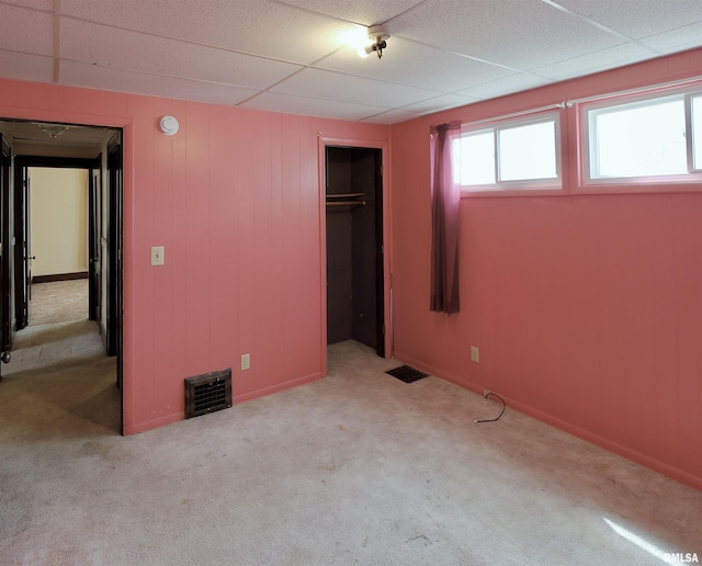 unfurnished bedroom with carpet, a closet, and a paneled ceiling