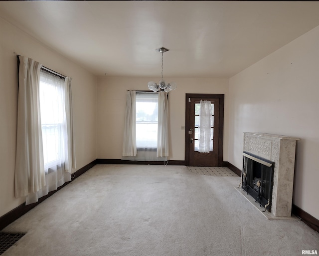 unfurnished living room featuring a chandelier, baseboards, light carpet, and a high end fireplace