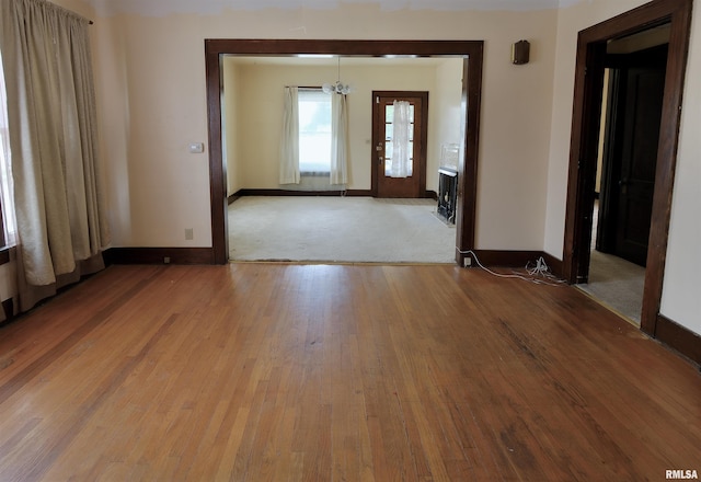 spare room with a chandelier, baseboards, and hardwood / wood-style floors