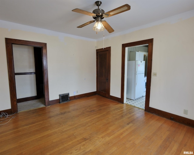 unfurnished room with baseboards, light wood finished floors, and ceiling fan