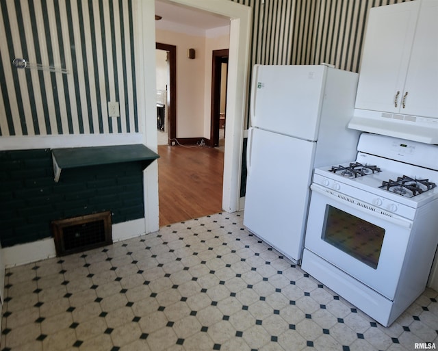 kitchen featuring white appliances, under cabinet range hood, wallpapered walls, light floors, and white cabinets