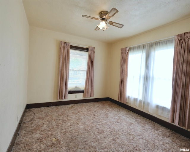 empty room featuring baseboards, ceiling fan, and carpet
