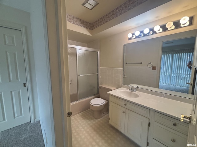 920 17th St Unit 28, Moline, IL 61265 - full bath with vanity, tile walls, toilet, wainscoting, and shower / bath combination with glass door