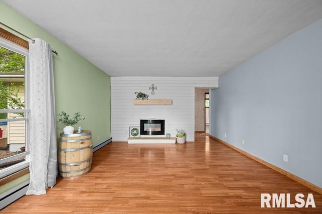 living room featuring baseboard heating, a large fireplace, and wood finished floors
