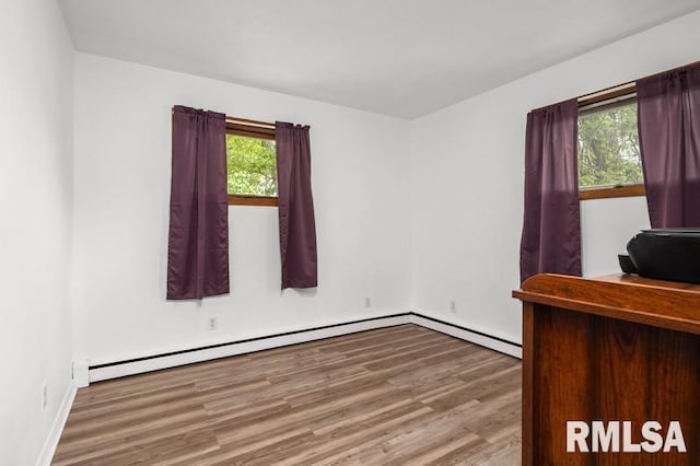 office with wood finished floors, plenty of natural light, baseboards, and a baseboard heating unit
