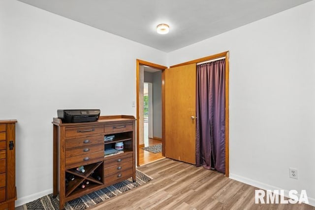 bedroom with light wood-style floors, baseboards, and a closet