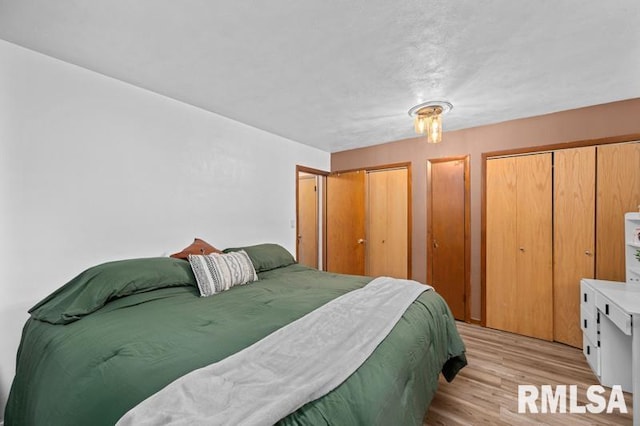 bedroom with two closets and light wood-style floors