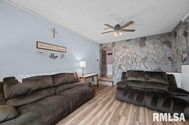 living room with a textured ceiling, a ceiling fan, and wood finished floors