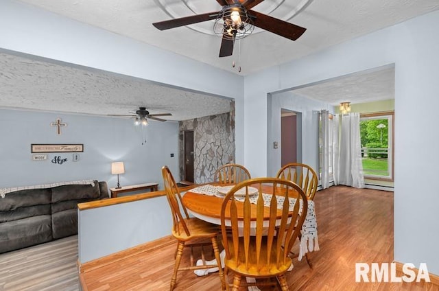 dining area with wood finished floors, a ceiling fan, a textured ceiling, and a baseboard heating unit