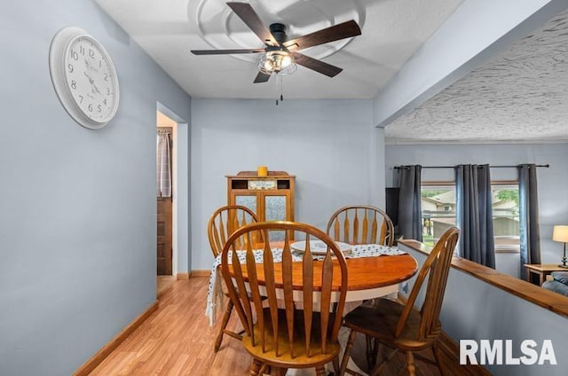 dining room featuring a ceiling fan, light wood-style flooring, and baseboards