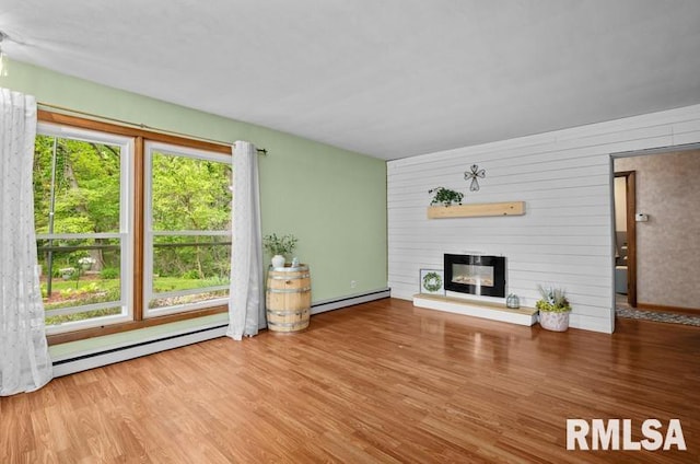 unfurnished living room featuring a baseboard heating unit, a baseboard radiator, wood finished floors, a fireplace, and baseboards