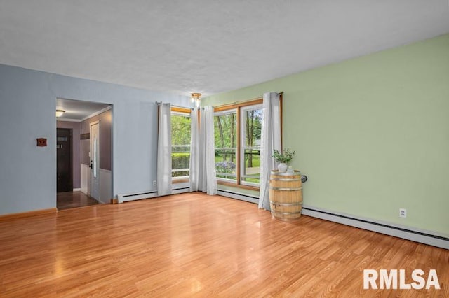 empty room with wood finished floors, baseboards, and a baseboard radiator